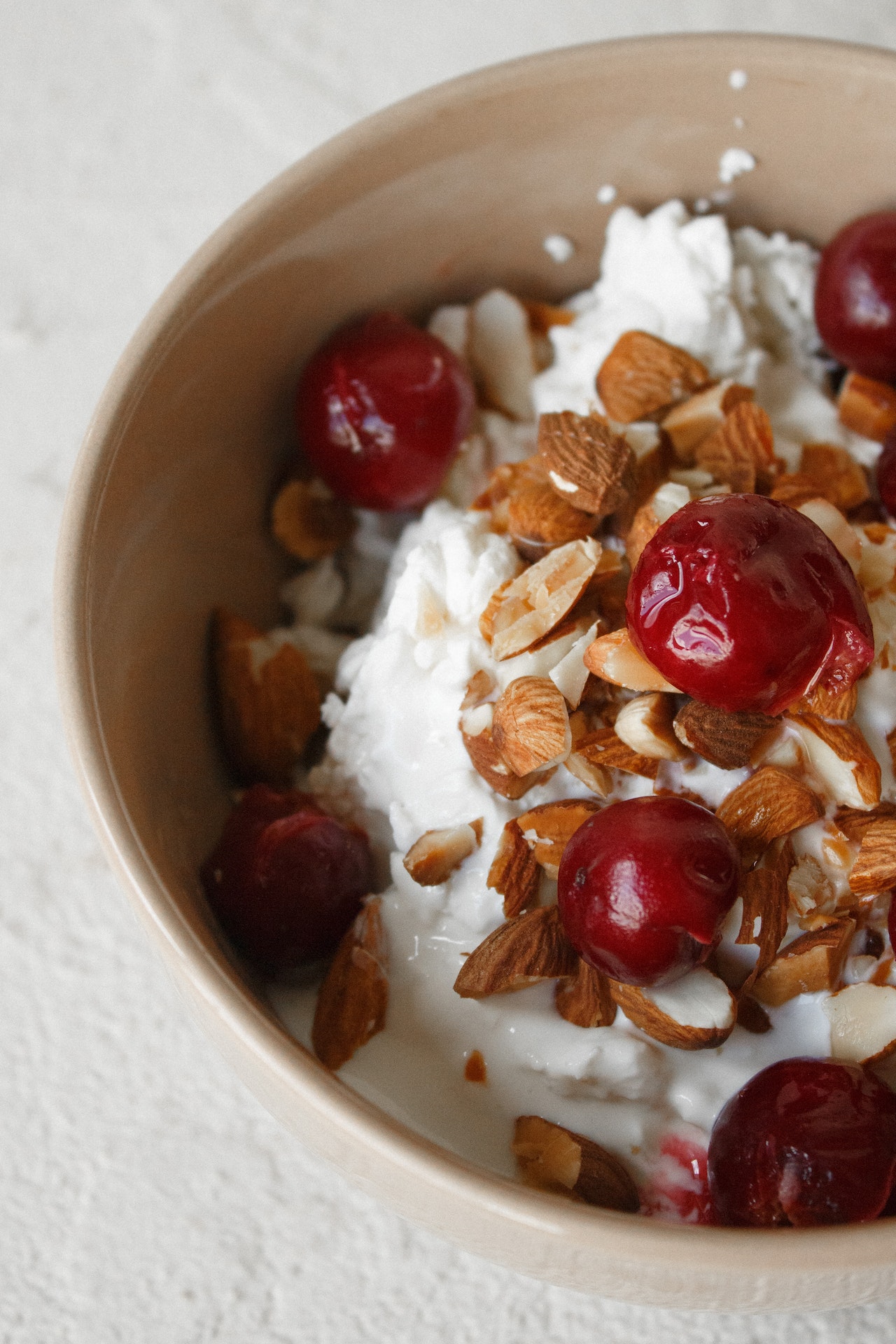 a bowl of cottage cheese topped with almonds and cherries.