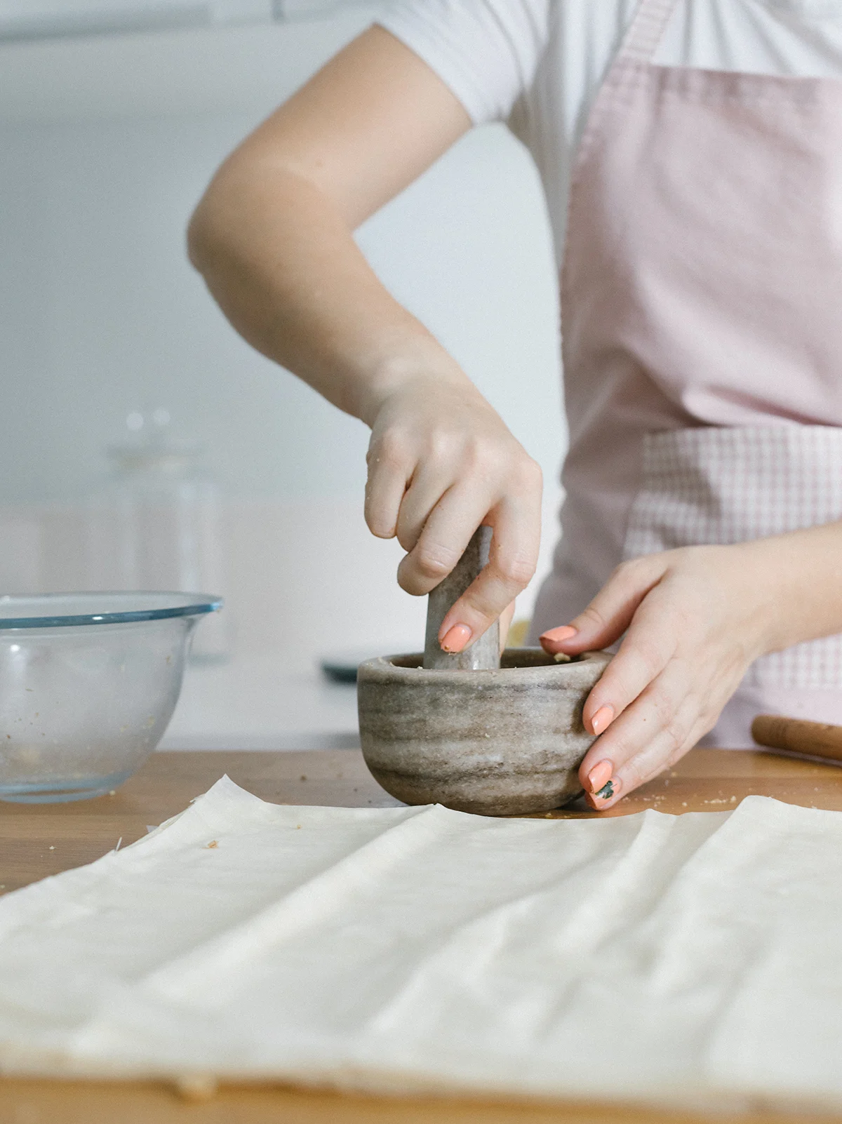 a woman using a mortar and pestle in a white kitchen.