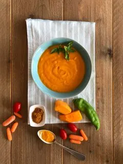 a bowl of orange carrot puree on a wooden table.