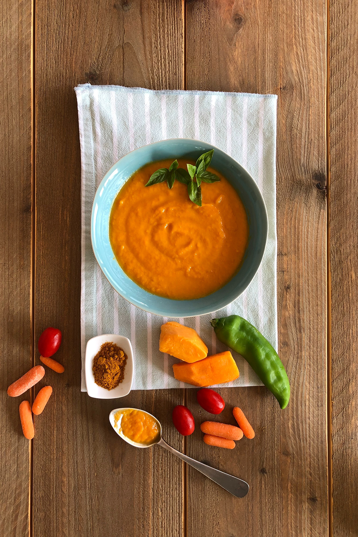 a bowl of orange carrot puree on a wooden table.