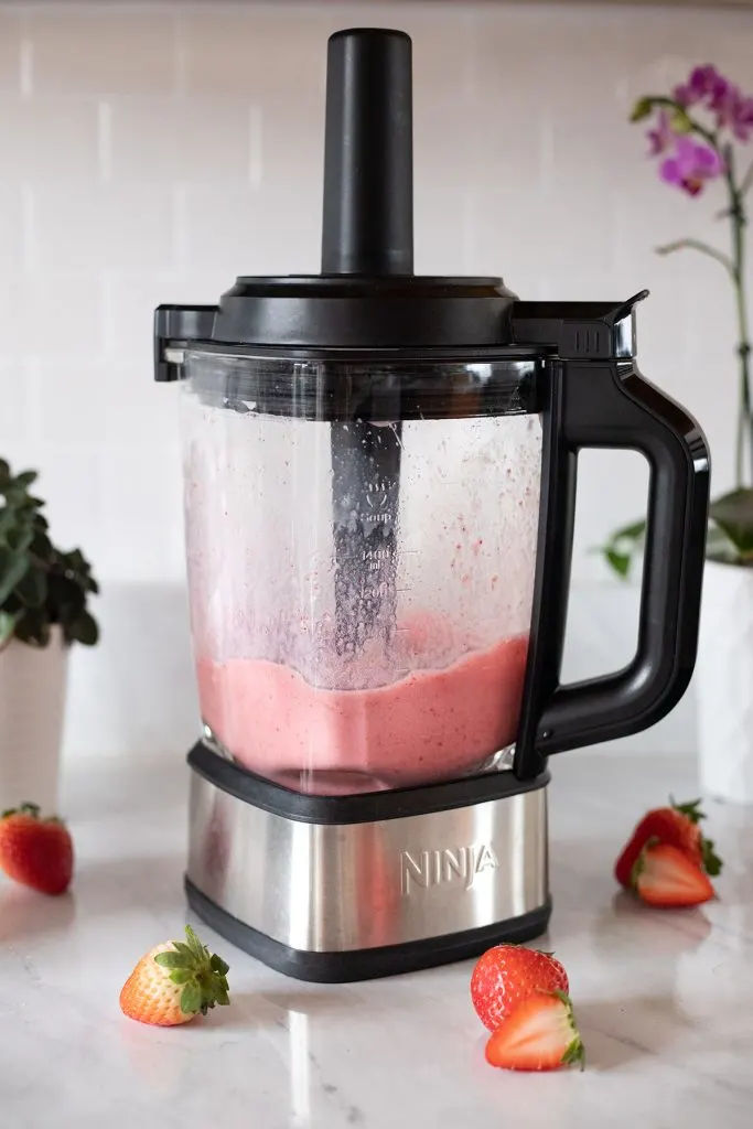 a ninja blender filled with a bright pink smoothie.