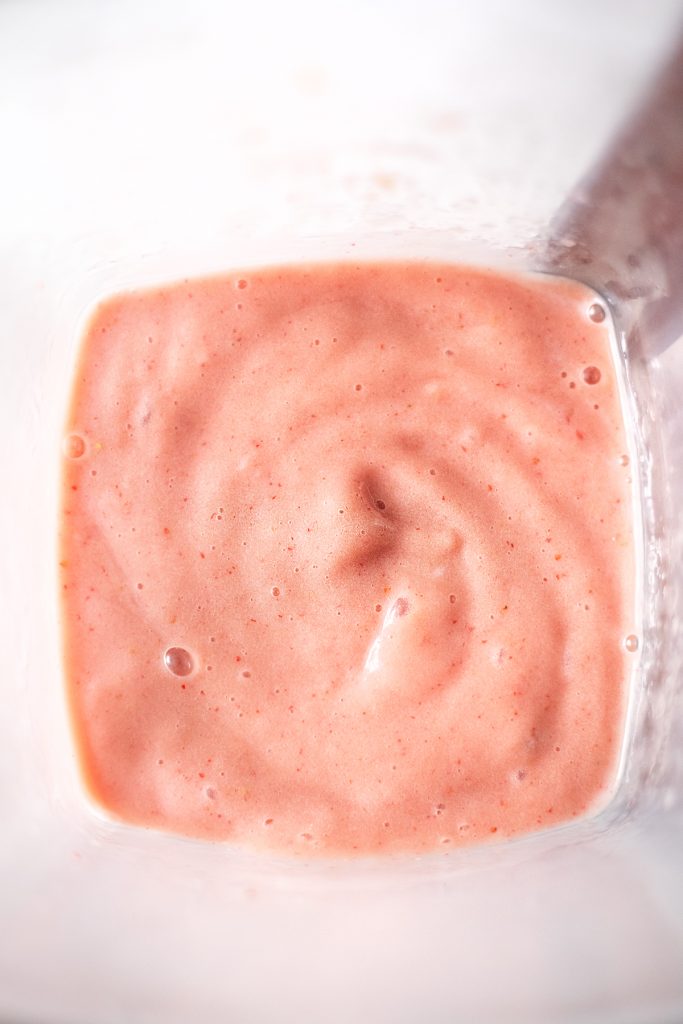 view of a pink smoothie in a blender pitcher.