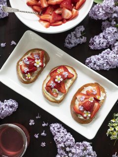 three slices of toast with strawberries and lilac blossoms.