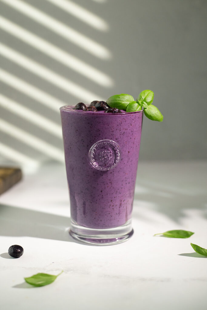 a dark purple smoothie on a white table.