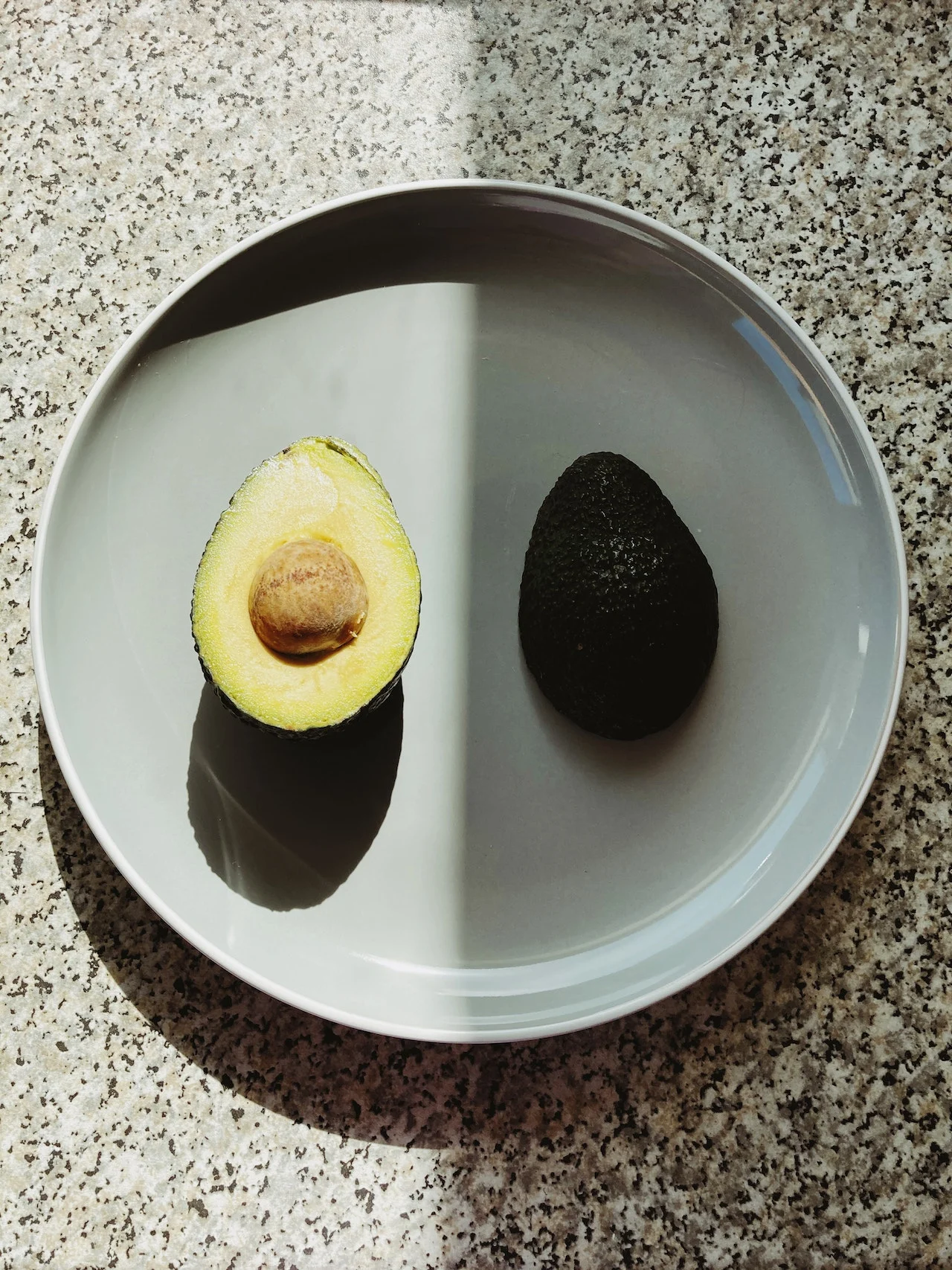 a gray plate with two avocado halves.